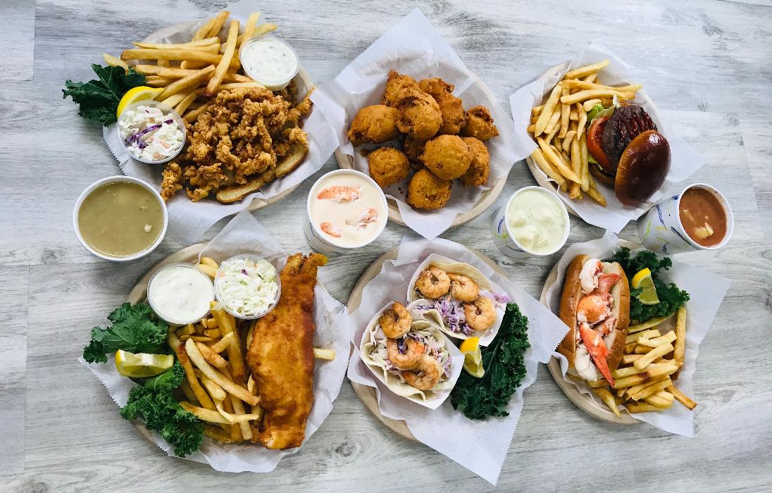 A variety of Chevy's Shack Hot Seafood Menu Options: Chowder, Fish & Chips, Shrimp Tacos, Lobster Roll, Clam Cakes, Burger & Fries and Clam Strip Plate